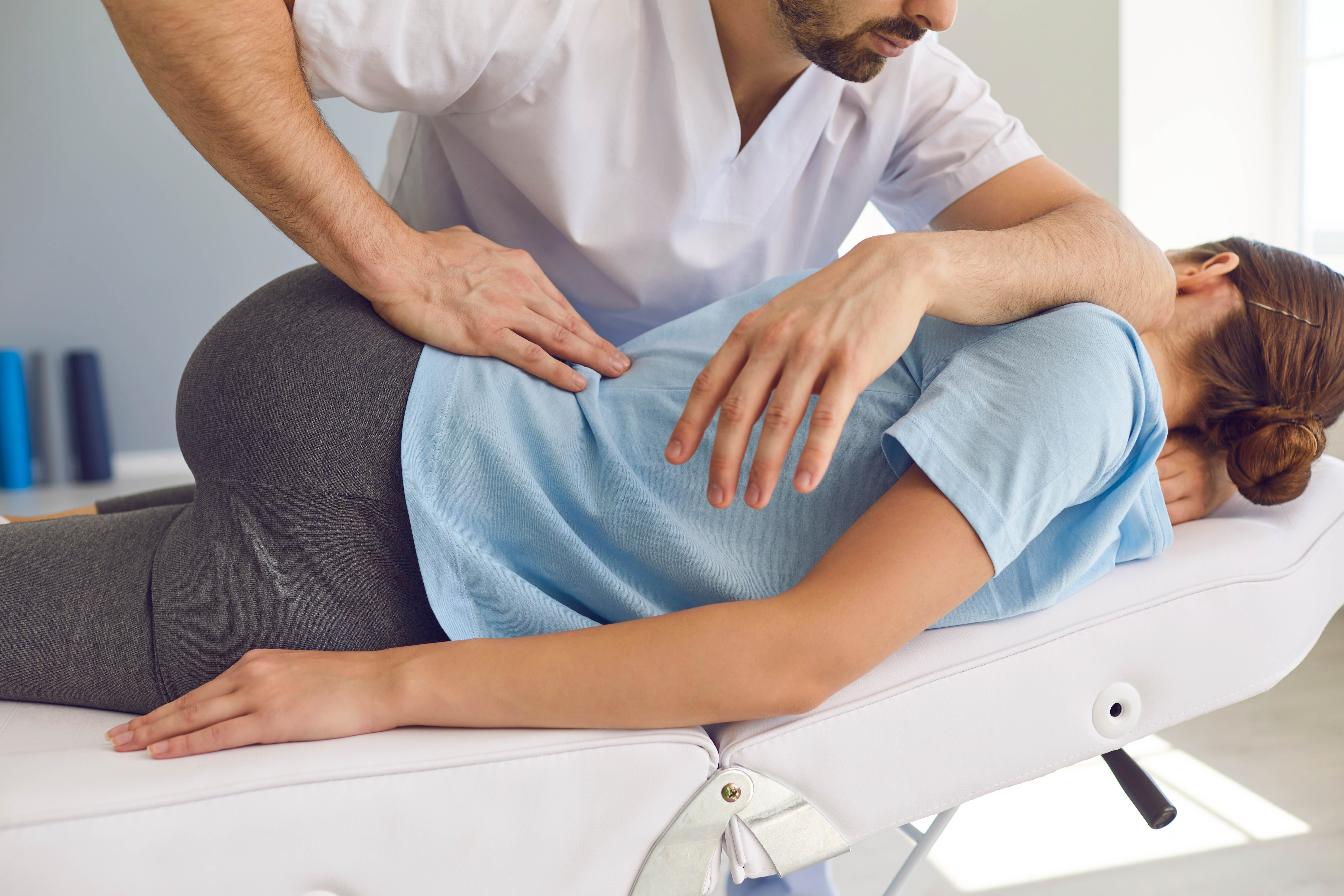 Chiropractor doing a chiropractic adjustment on a patient's back in the clinic